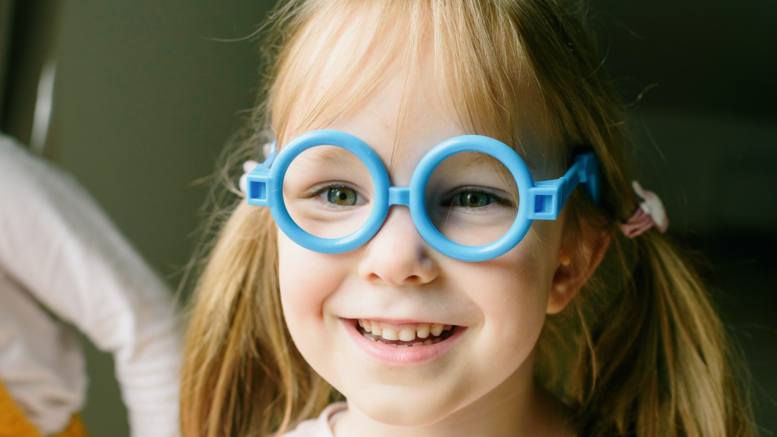fetiță cu ochelari de vedere care zâmbește frumos